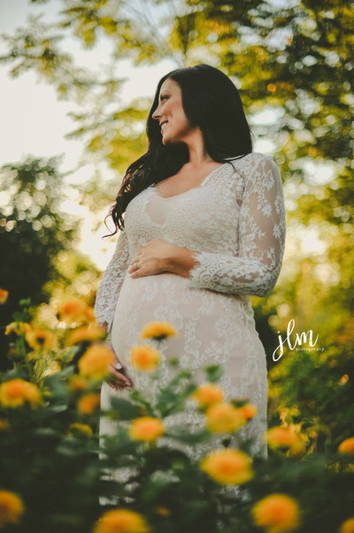 this is a maternity photography image of a pregnant women in a field of flowers 