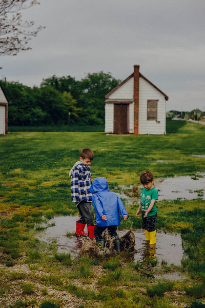 this boys are jumping in a puddle after rainfall in long island during a summer mini session 