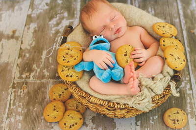 a newborn baby holding cookies and cookie monster 